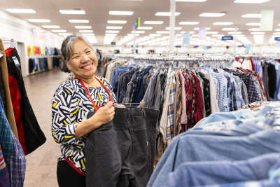 thrift store employee hangs clothes on the retail floor at Deseret Industries