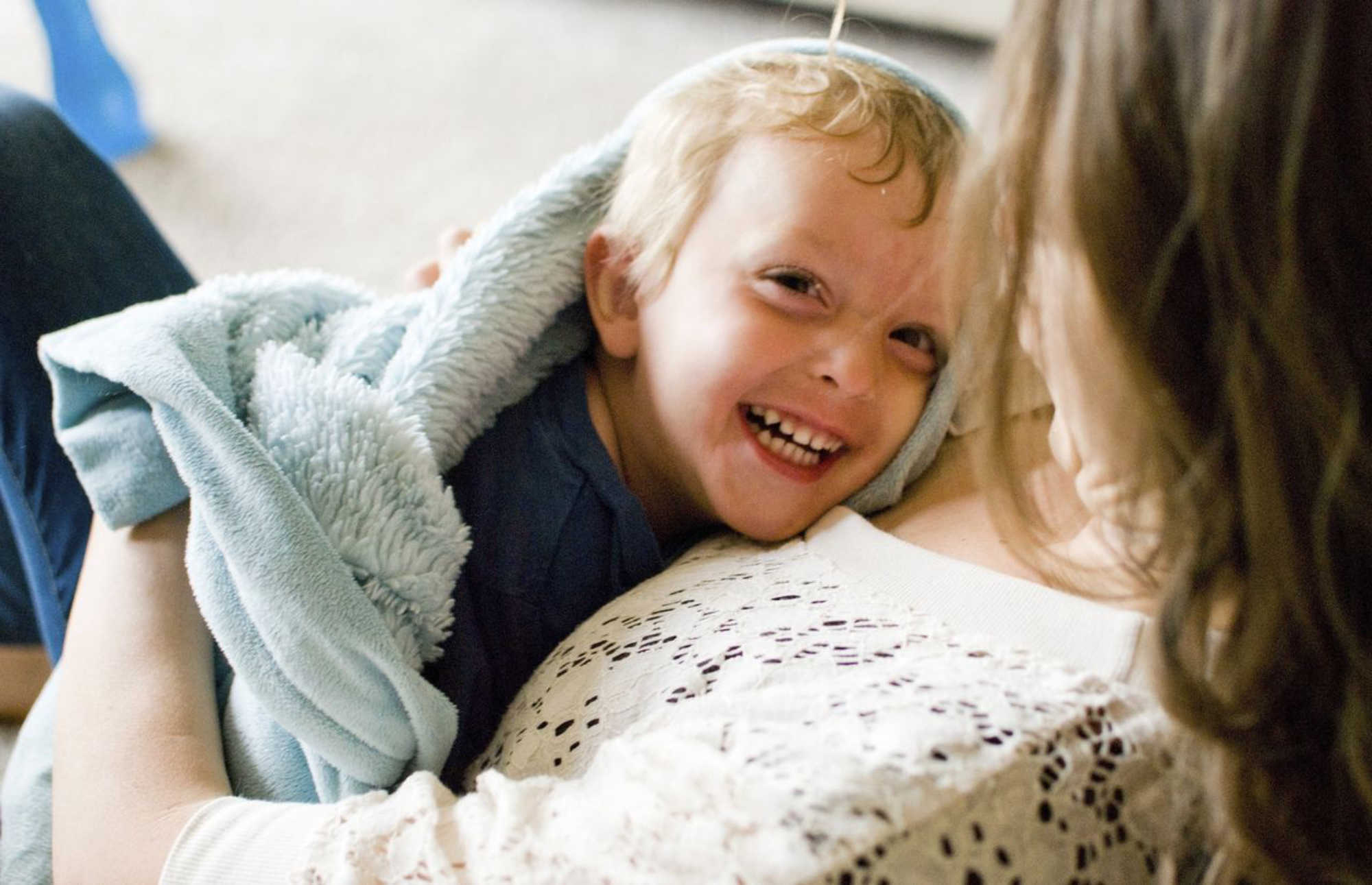 kid in a blanket smiling at woman