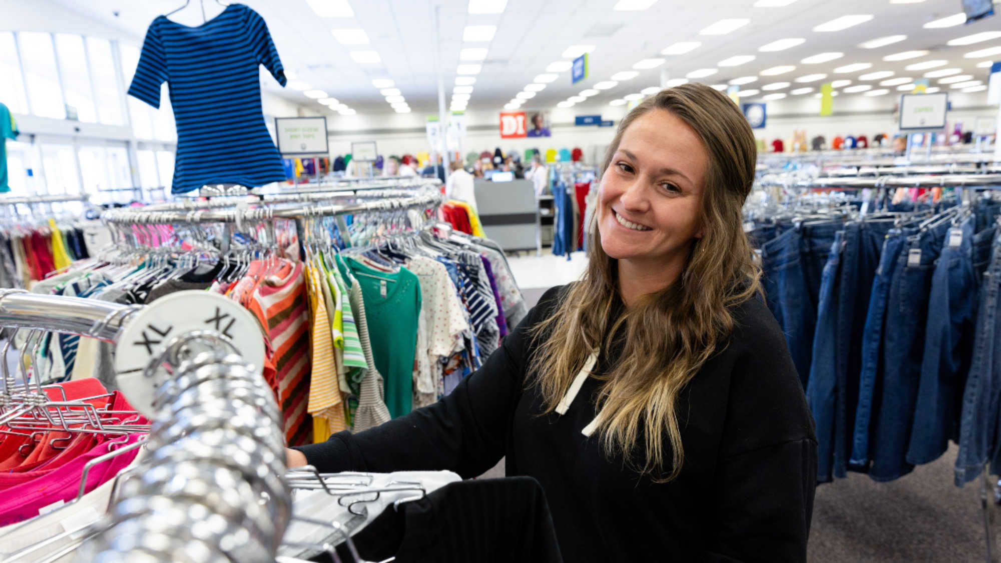A woman smiles at the camera as she shops for children's clothing at her local Deseret Industries store.