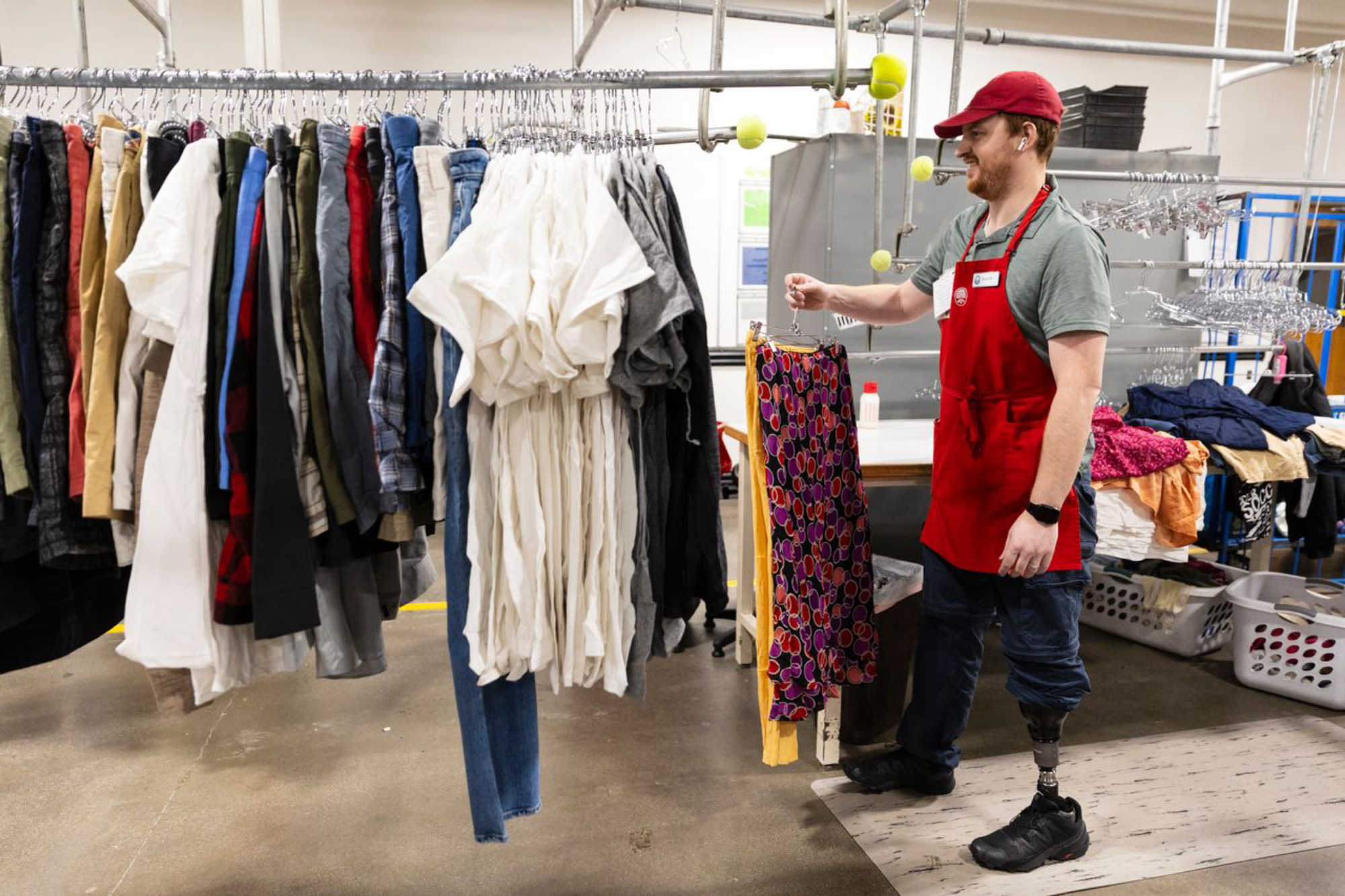 DI associate hangs clothes for sorting in job training program