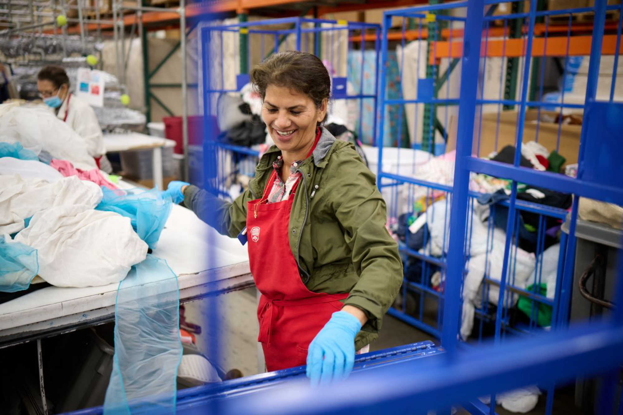 a thrift store worker in a red apron helps sort donations at Deseret Industries