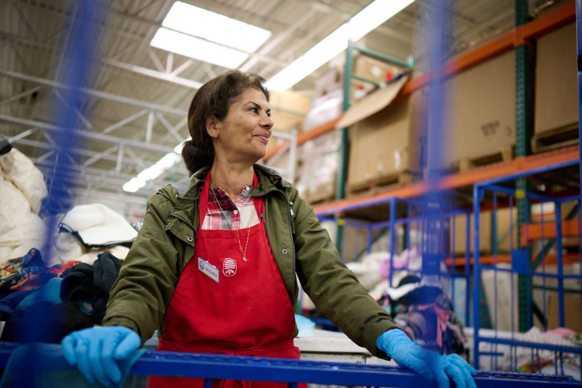 a thrift store worker in a red apron helps sort donations at Deseret Industries