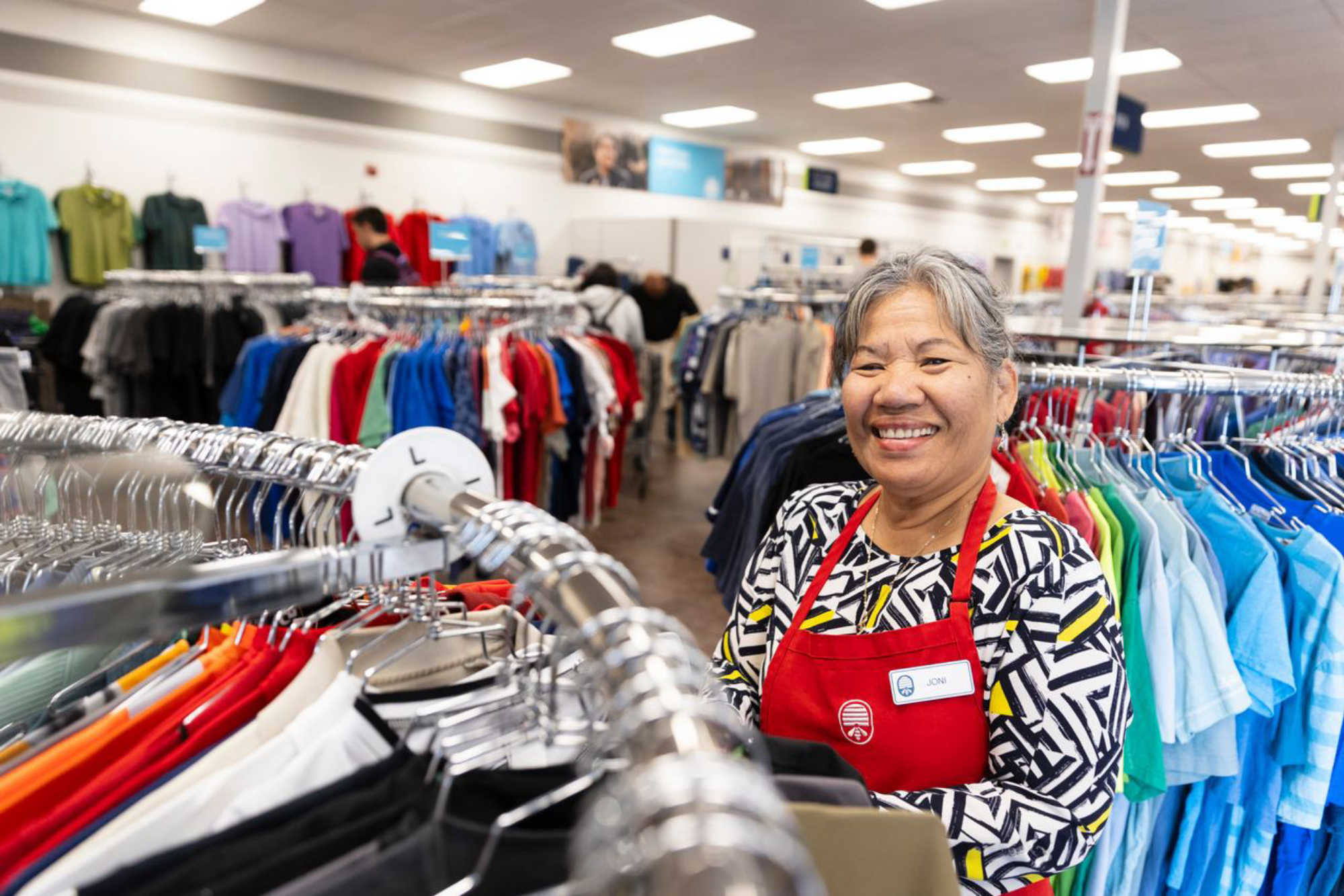 thrift store employees organize clothes on the retail floor