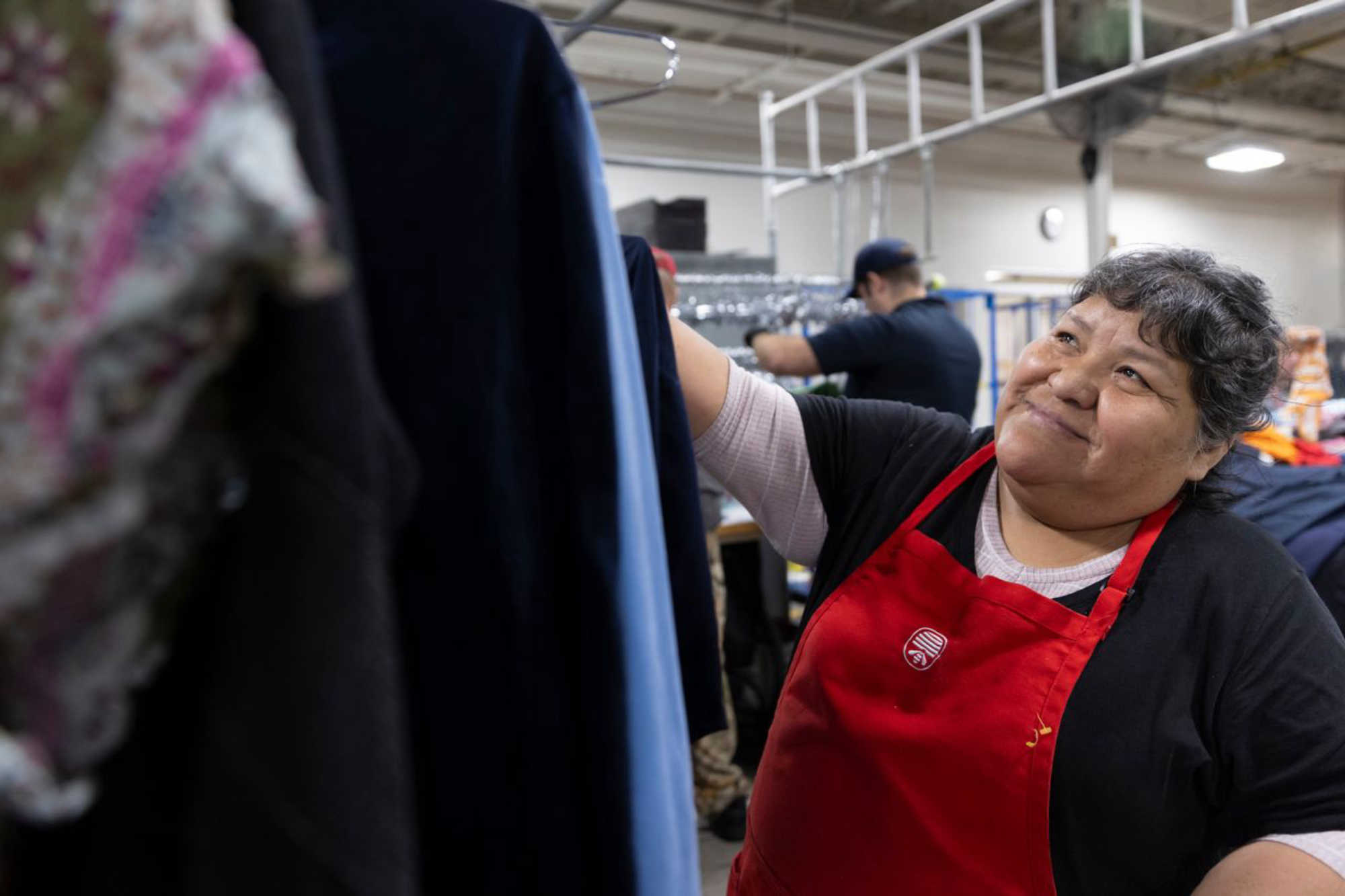 a Deseret Industries associate hangs donated clothing up on a rack