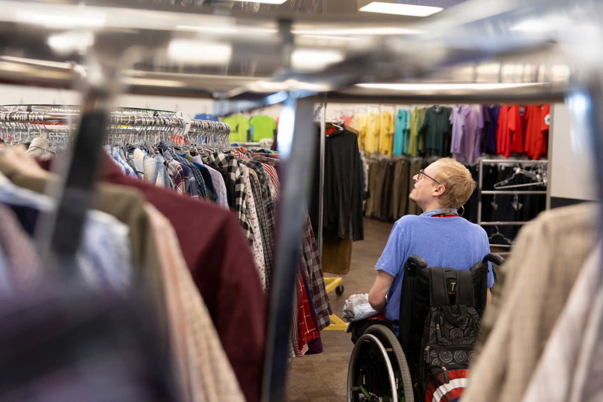 thrift store employee helps hang up clothes on the retail floor at Deseret Industries