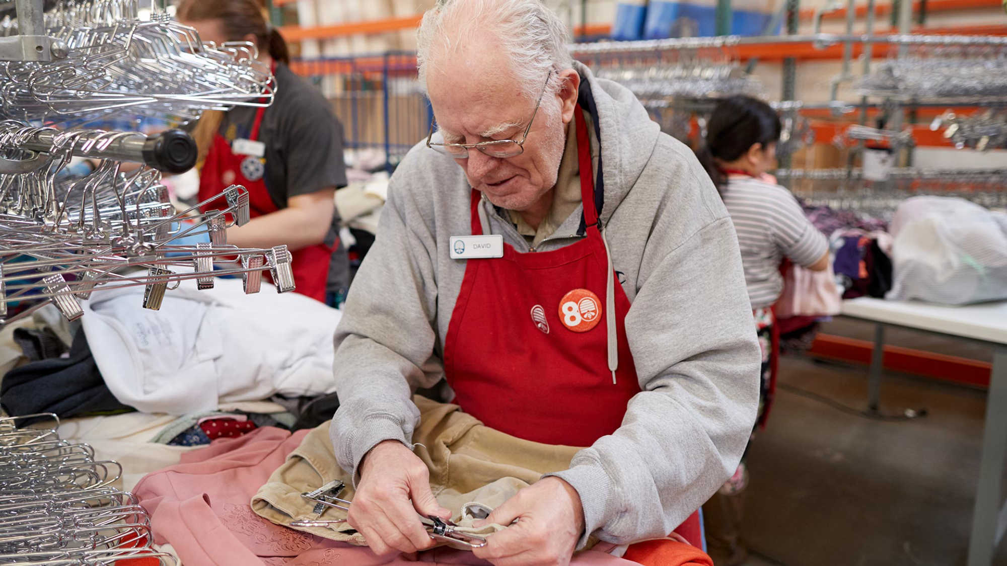 Associate David hangs donated pants on a hanger at DI